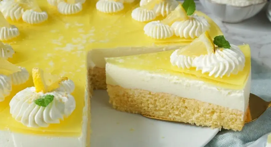 Erfrischende joghurt-torte mit biskuitboden, dekoriert mit Zitronenspalten und Sahnetupfern.