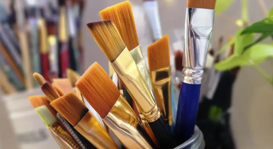 Un pot rempli de pinceaux aux poils orangés, prêts à être utilisés avec un nettoyant peinture acrylique.