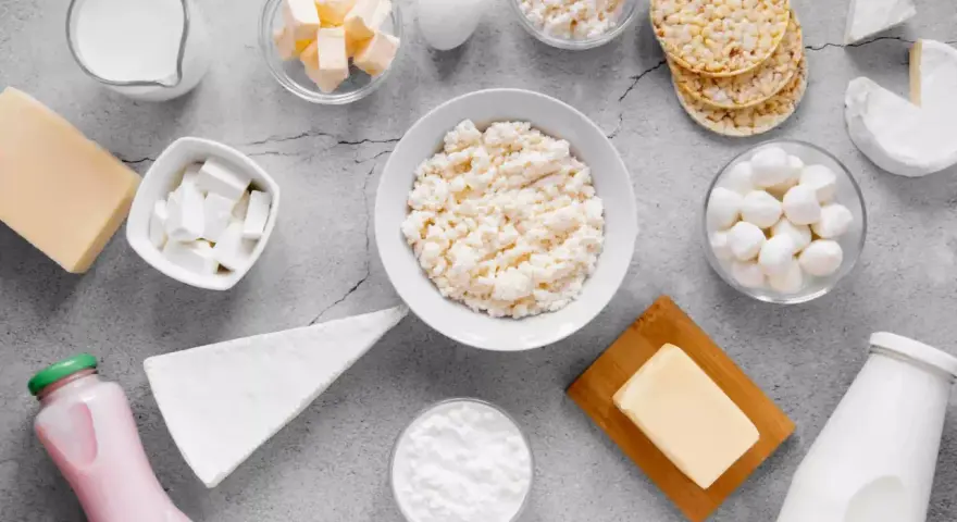Różnorodne produkty bogate w wapń: mleko, sery, jogurt, masło, jajko i wafle ryżowe.