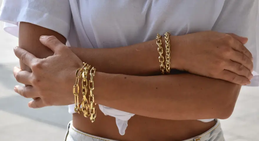 Bracciali in oro 18 carati, più brillanti e preziosi rispetto all'oro 9 carati, adornano le braccia di una donna.