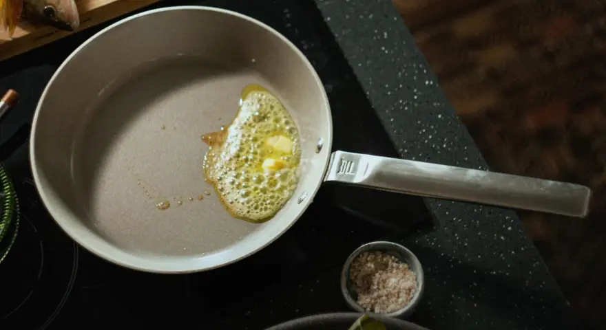 Butter schmilzt in einer beschichteten Pfanne, bereit für Fisch. Die Pfanne ist leicht zu reinigen.