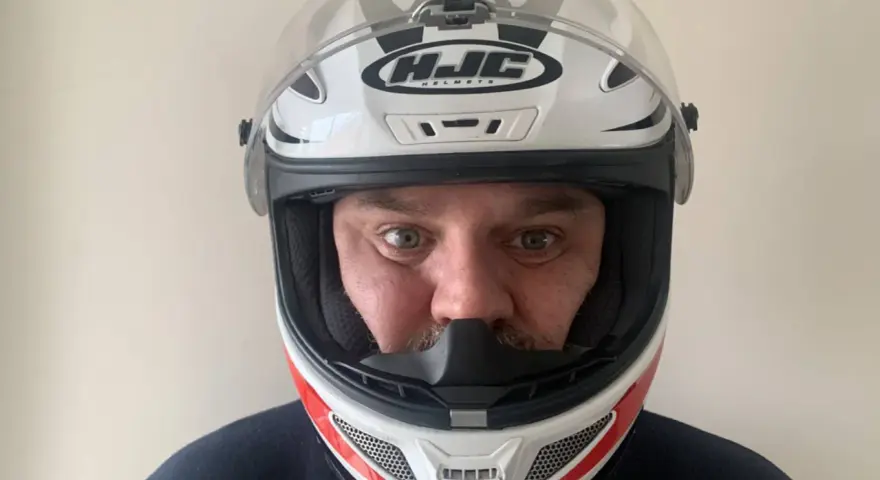 Hombre con casco HJC blanco y rojo, listo para elegir su equipo de moto.