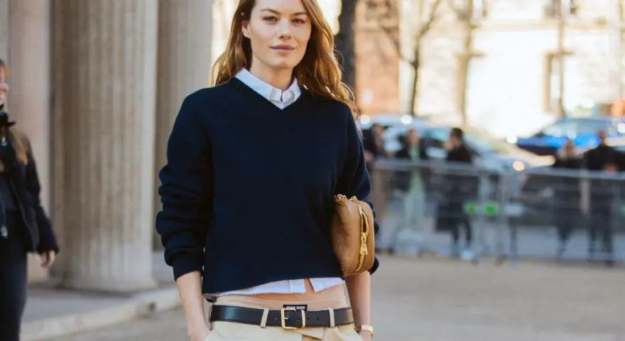 Modello con maglione blu scuro, camicia bianca e pantaloni beige. Un'idea su come vestirsi per uscire con stile.