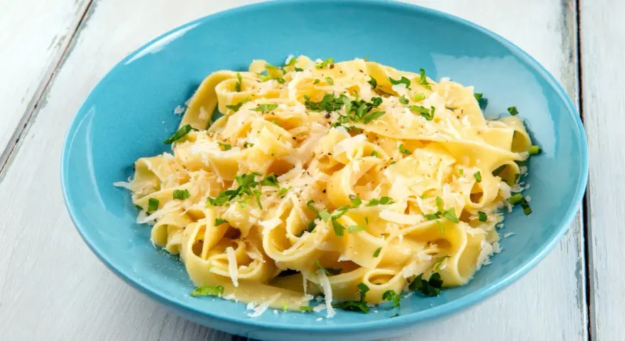 Fettuccine al burro e parmigiano, uno dei sughi per pasta più semplici e gustosi, guarnito con prezzemolo fresco.