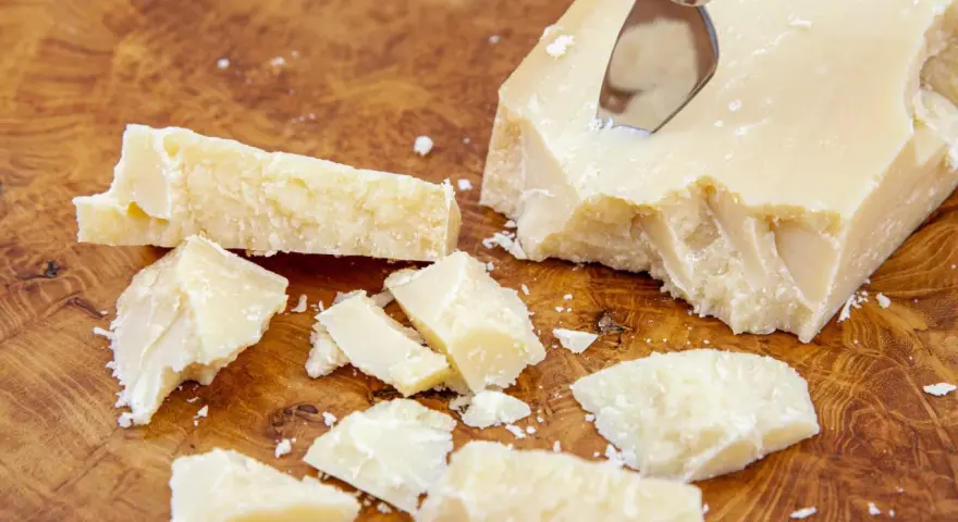 Kawałki parmezanu, znanego też jako Grana Padano, na drewnianej desce.
