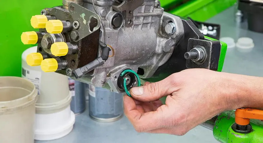 Hand replaces a green O-ring on a Bosch Einspritzpumpe, part of the process to einspritzpumpe reparieren.