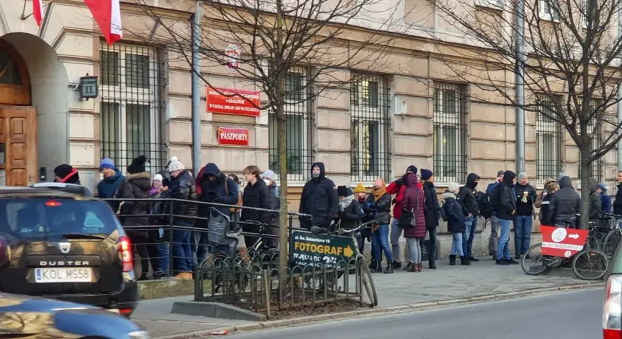 Kolejka do odbioru paszportu w Krakowie. Ludzie stoją przed budynkiem urzędu.