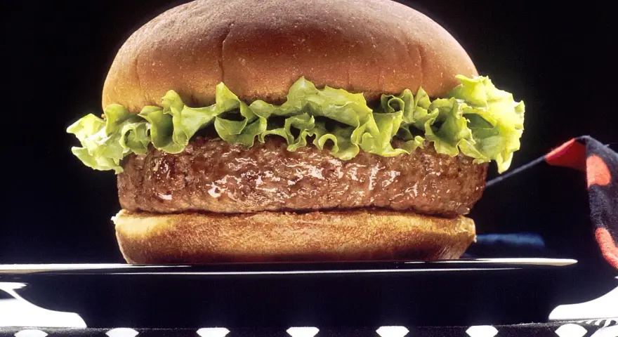 Soczysty hamburger z sałatą na czarnym talerzu.
