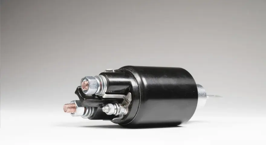 A black starter solenoid with copper and silver bolts, ready to power up an engine.