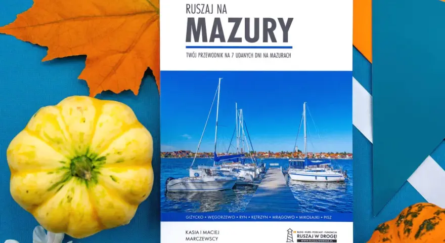 Przewodnik "Ruszaj na Mazury" z widokiem na żaglówki i miasteczko. Idealny na podróż po krainie tysiąca jezior.