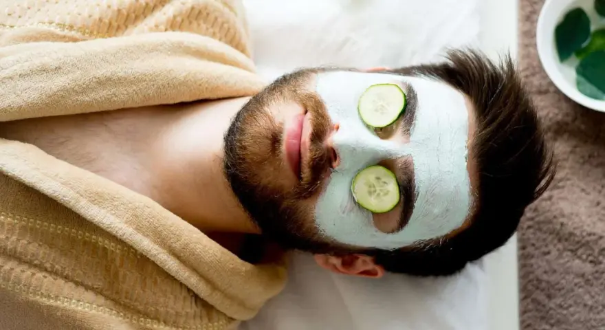 Man with a face mask and cucumber slices on eyes, relaxing. Wondering how long to keep face mask on for best results.