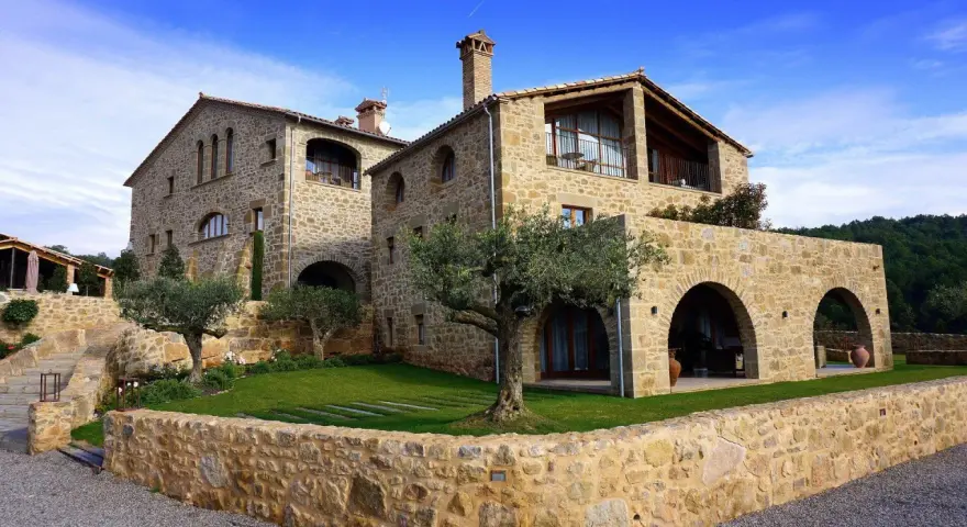 Magnifique maison en pierre calcaire avec des arches et un jardin verdoyant.