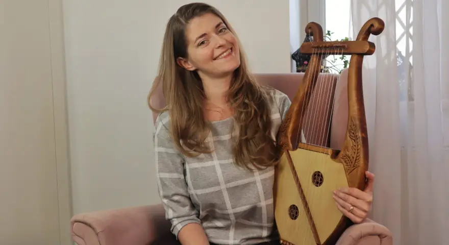 Uśmiechnięta kobieta trzyma instrument muzyczny, który wygląda jak skorupa żółwia.