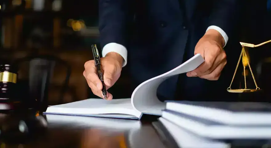 Un avocat examine des documents, une balance de la justice et un maillet sur un bureau. Il semble qu'il soit confronté à une situation où je ne peux pas payer la prestation compensatoire.