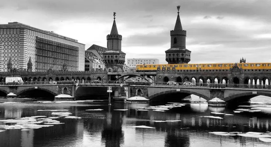 Gelbe U-Bahn fährt über die Oberbaumbrücke in Berlin. Eisschollen treiben auf dem Wasser.