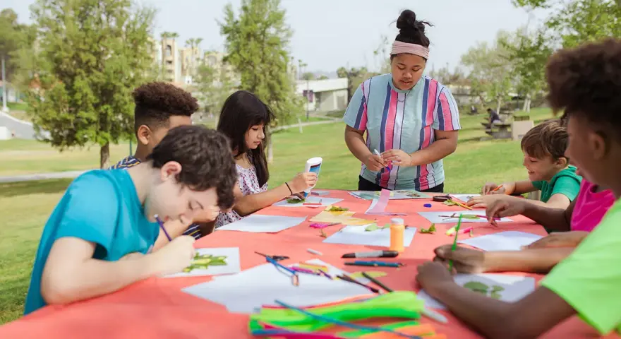 Des enfants créatifs participent à un atelier d'art en plein air, une activité typique d'un centre de loisirs ou d'un camp d'été, peut-être dans le cadre d'un programme ACM BAFA.