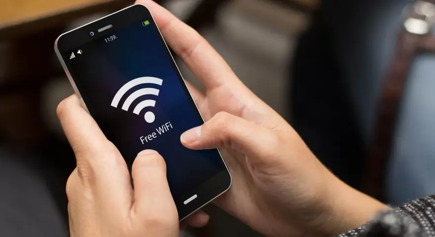 Dłonie trzymają smartfon z ikoną Wi-Fi i napisem "Free WiFi". Zastanawiasz się, co pobiera najwięcej internetu w telefonie?