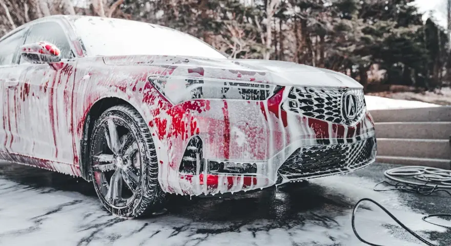 Czerwony samochód pokryty pianą, myty w zimnie. Czy można myc auto w mrozie? Tak, jeśli użyjesz odpowiednich środków.