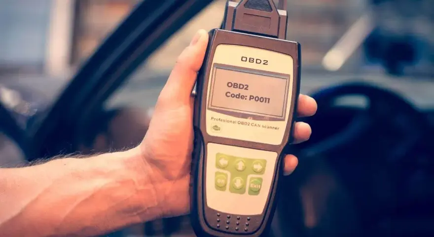 Hand holding an OBD2 scanner displaying code P0011, ready to diagnose car issues.
