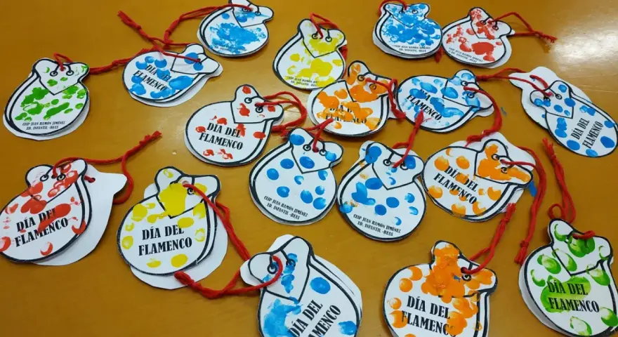 Manualidades flamencas para niños: castañuelas de papel con huellas dactilares de colores, decoradas para el Día del Flamenco.