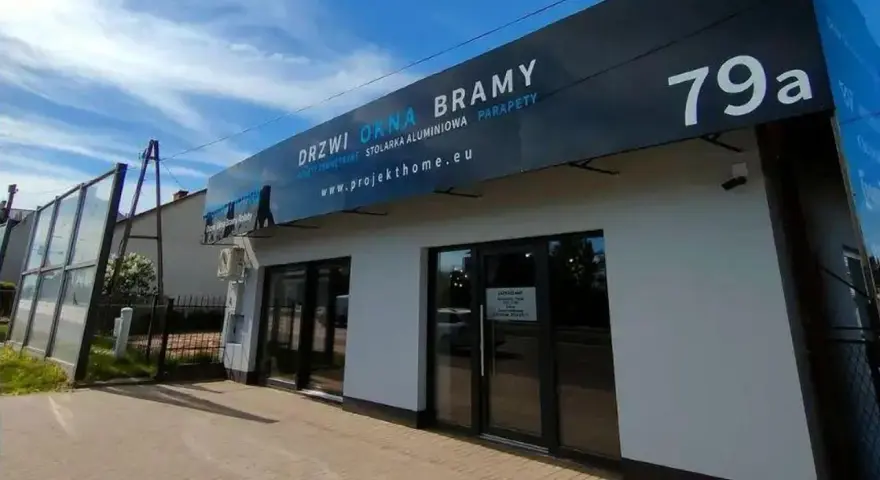 Nowoczesny salon z oknami i drzwiami, z szyldem "DRZWI OKNA BRAMY" i numerem 79a.