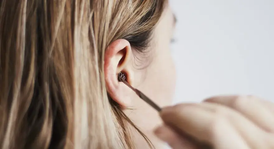 Une personne utilise un outil pour nettoyer son oreille. Les boules quies me font mal aux oreilles, alors je préfère cette méthode.