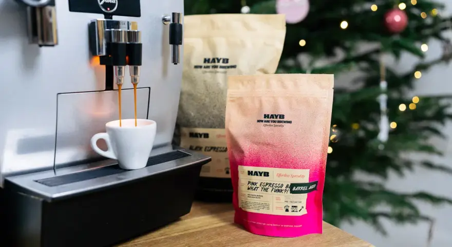Espresso z ekspresu Jura, obok paczki kawy HAYB "Pink Espresso Barrel Aged". W tle choinka.