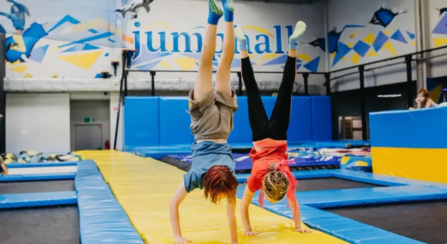 Dzieci robią stanie na rękach na trampolinach w sali gimnastycznej.