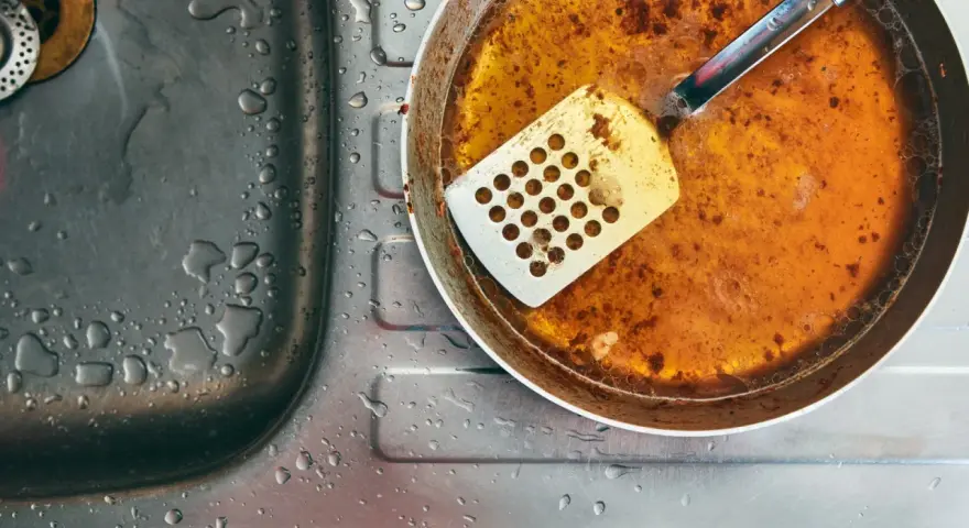 Zlepek zużytego oleju gastronomicznego na patelni obok zlewu.