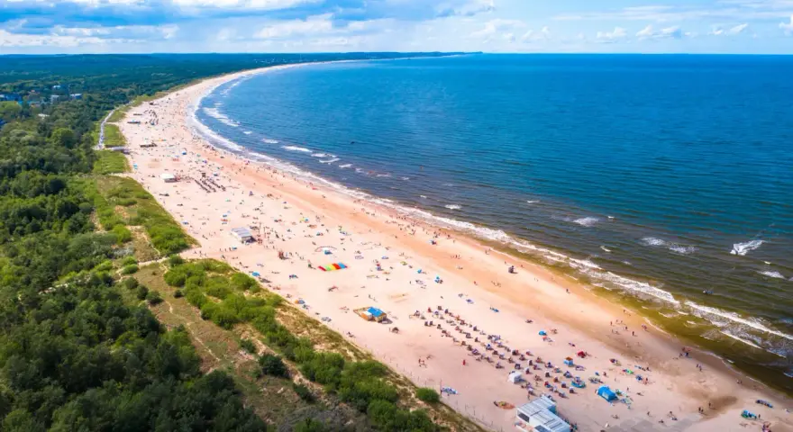 Szeroka, piaszczysta plaża z tłumem turystów, zielony las i błękitne morze – to jedne z najpiękniejszych plaż w Polsce.