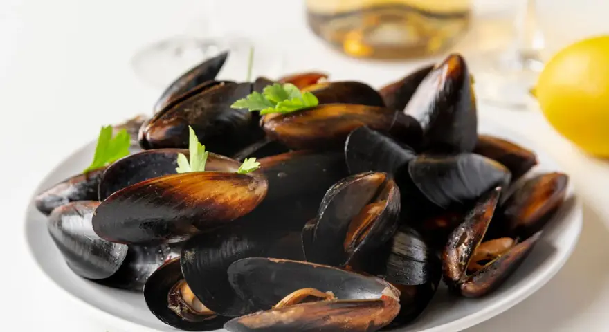 Plato de mejillones al vapor, listos para disfrutar con un toque de limón y perejil.