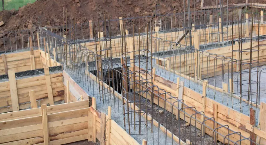 Drewniany szalunek fundamentowy z zbrojeniem stalowym, gotowy do wylania betonu.