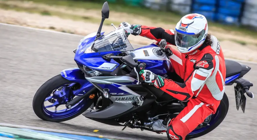 Motocyklista w czerwonym kombinezonie i kasku ściga się na torze na motocyklu Yamaha R3.