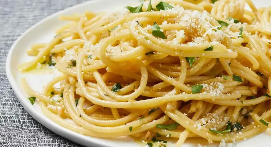 Pyszny makaron aglio e olio, idealny pomysł, z czym zrobić makaron na szybko. Posypany parmezanem i natką pietruszki.