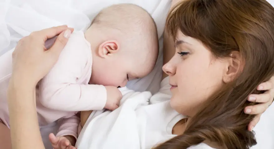 Mama tuli tulista, kpi karmienie. Dziecko przytulone do piersi, spokojne i bezpieczne.