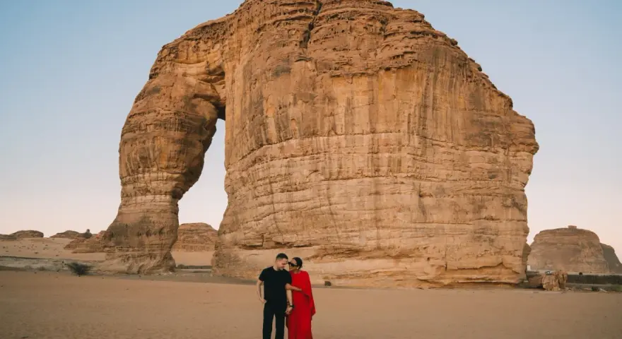 Coppia romantica davanti alla Roccia Elefante, una delle meraviglie naturali da vedere in Arabia Saudita.