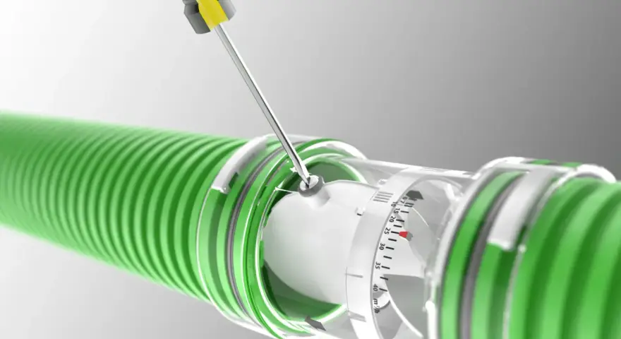A screwdriver adjusts a clear dial on a green hose, indicating the regulador caudal.
