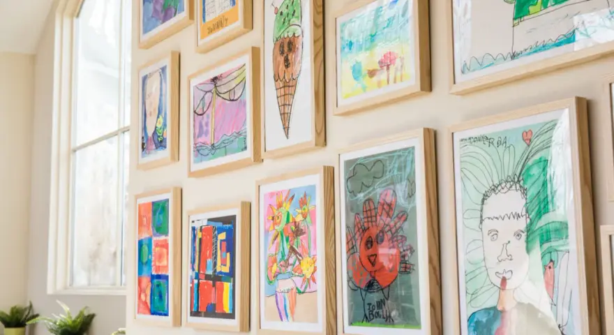 Un colorido cuadro para niños exhibe dibujos de helados, flores y retratos, cada uno enmarcado en madera clara.