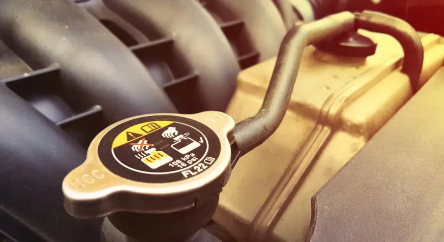 A car's radiator cap, showing warnings about hot coolant. A faulty cap can cause overheating, one of the bad radiator cap symptoms.