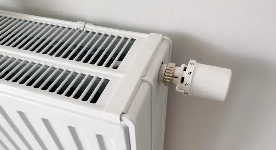 Biały grzejnik z termostatem. Dowiedz się, jak odpowietrzyć grzejnik, gdy przestaje efektywnie grzać.