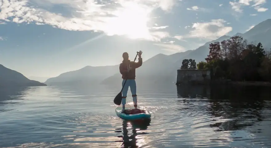 Person auf einem Stand Up Paddle Board, genießt die Aussicht und verbrennt dabei effektiv Stand Up Paddle Kalorien.