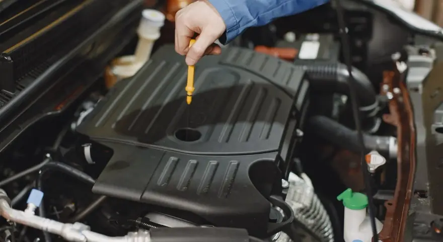 Mechanik sprawdza poziom oleju w silniku Peugeot 508. Wymiana oleju w skrzyni manualnej to ważny element dbania o auto.