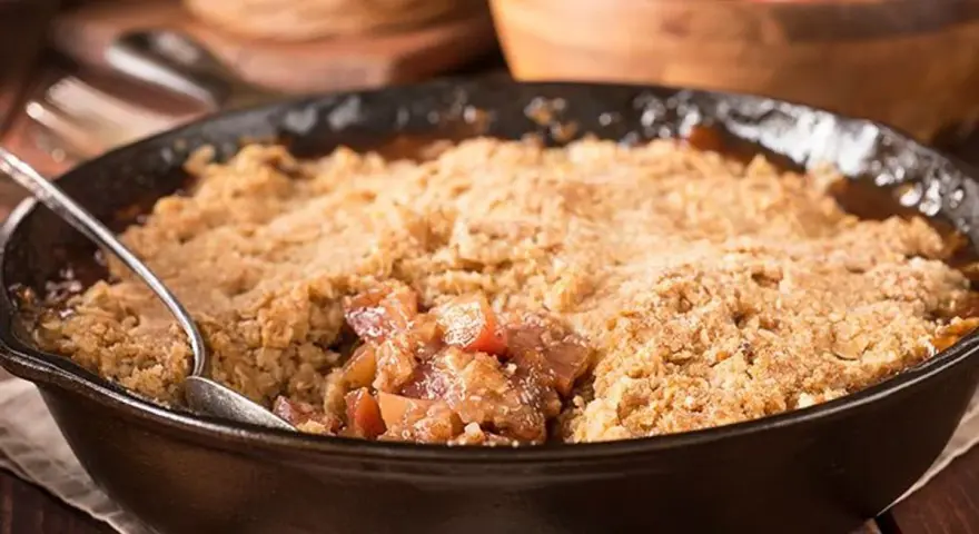 Un délice de pâte à crumble croustillante sur un lit de fruits fondants, servi dans une poêle en fonte.