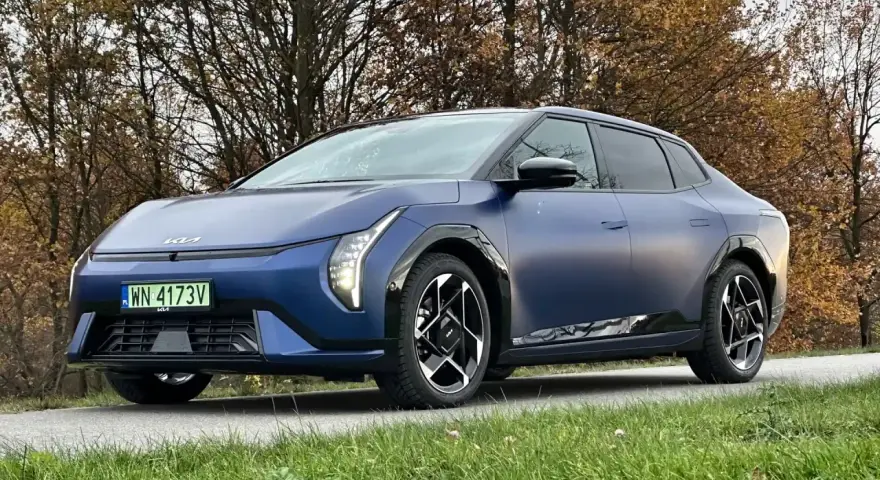 Niebieski Polestar 2 na tle jesiennych drzew. Elegancki samochód elektryczny z charakterystycznymi światłami i felgami.