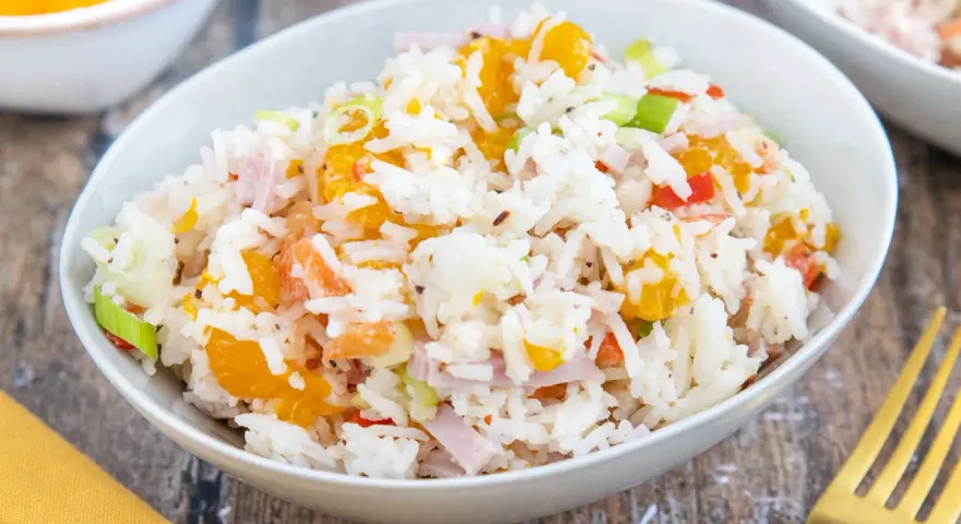 Omas Reissalat mit Orangenstücken, Schinkenwürfeln und Frühlingszwiebeln in einer Schüssel.
