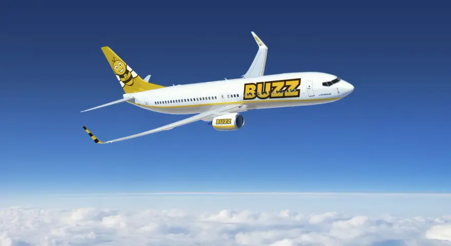 Samolot Buzz, należący do Ryanair, leci nad chmurami. Idealny na wakacje, zabierze Twój bagaż w słoneczne miejsce.