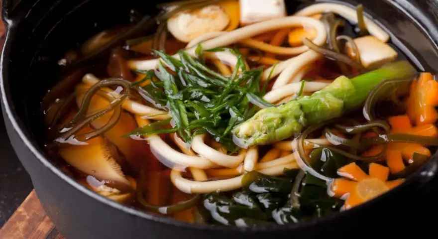 Aksamitny bulion dashi, w którym pływają grube kluski udon, tofu, marchewki w kształcie kwiatków, zielone warzywa i wodorosty. Pyszne i zdrowe danie.