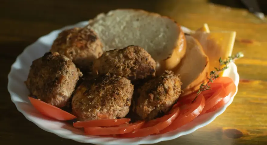 Talerz z kotletami mielonymi, kromkami chleba, pomidorami i serem. Idealny posiłek, jeśli zastanawiasz się, jaki kotlet mielony kcal.