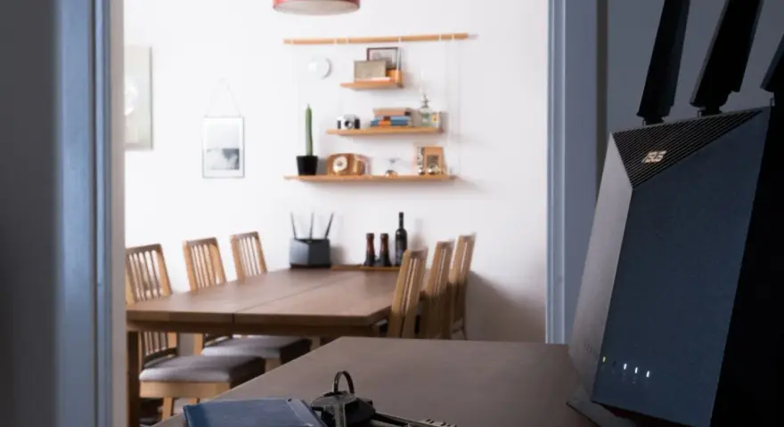 En modern router med wifi 4 ger snabb uppkoppling i hemmet. Nycklar och en blå korthållare ligger på bordet.