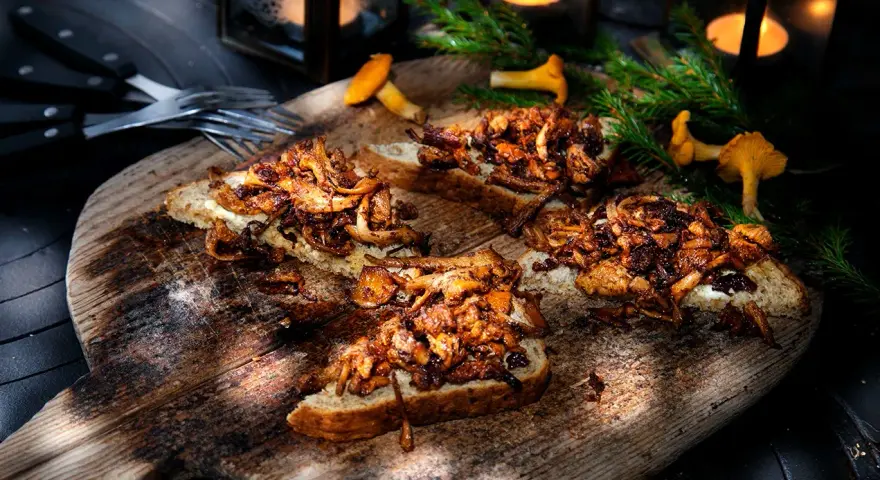 Smörstekta kantareller på bröd, ett enkelt och gott kantareller recept. Serveras på en träbricka med ljus och granris.